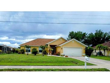 Charming one-story home featuring lush green lawn, mature landscaping, and attached two-car garage at 1185 Rio De Janeiro Ave, Punta Gorda, FL 33983