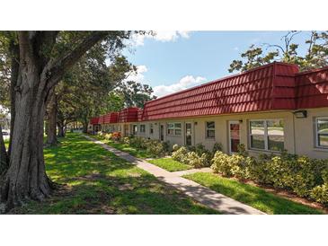 Charming condos with red roofs line a sidewalk through a well-maintained lawn and mature trees at 5870 38Th N Ave # 44, St Petersburg, FL 33710