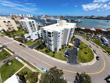 Stunning aerial view of a waterfront condo building with manicured lawns and ample parking at 855 Bayway Blvd # 908, Clearwater Beach, FL 33767