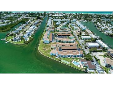 Aerial view showcasing waterfront condominiums with docks and lush landscaping at 1 Windrush Blvd # 84, Indian Rocks Beach, FL 33785
