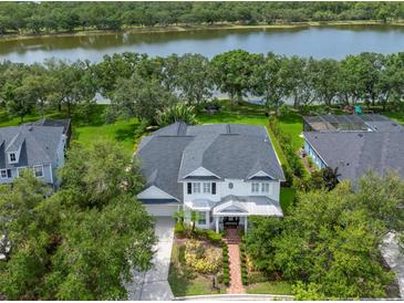 An aerial view of a well-maintained, two-story home with lake access, surrounded by lush greenery and manicured lawns at 14617 Galt Lake Dr, Tampa, FL 33626