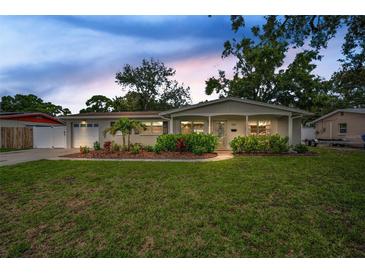Charming single-story home with a manicured lawn, lush landscaping, and an attached garage at 1557 77Th N Ave, St Petersburg, FL 33702