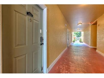 Condo hallway with yellow walls and red painted floor leading to bright outdoor area at 4207 S Dale Mabry Hwy # 2101, Tampa, FL 33611