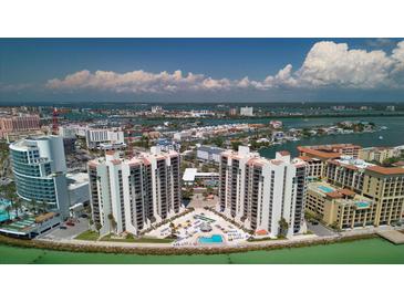 Stunning aerial view of condos with a waterfront pool, lush landscaping, and panoramic city and ocean views at 440 S Gulfview Blvd # 701, Clearwater Beach, FL 33767