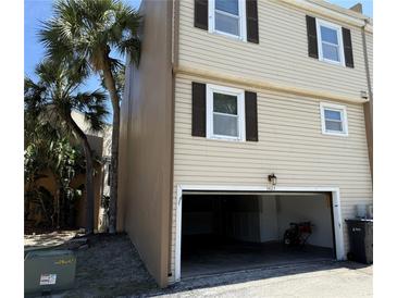 Beige townhouse showcasing a two-car garage with traditional dark brown shutters and palm tree views at 5423 Sweetwater Terrace Cir, Tampa, FL 33634