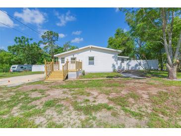 Quaint single-story home with a new deck and white siding nestled among mature trees at 9445 Cardy St, New Port Richey, FL 34654