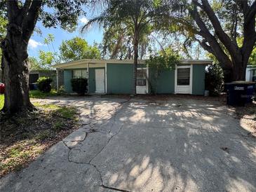 Quaint single-story home with a concrete driveway and mature trees providing shade in the front yard at 1511 Lynn Ave, Clearwater, FL 33755