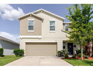 Two-story home featuring a two-car garage, neutral color scheme, manicured lawn, and small shrubs at 17156 Yellow Pine St, Wimauma, FL 33598