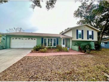 Charming home showcasing an attached garage, a well-manicured front yard, and inviting curb appeal at 2014 Nancy Ave, Lutz, FL 33548