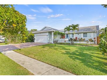 Charming single-story home with a lush green lawn, brick driveway and a beautiful mango tree in the front yard at 417 Manor Blvd, Palm Harbor, FL 34683