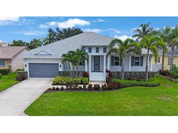 Beautiful exterior of a two-story home featuring manicured landscaping, a gray roof, and a gray two-car garage at 425 4Th N Ave, Tierra Verde, FL 33715
