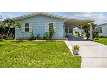 Charming light blue home with white trim, well-manicured lawn, and a covered carport at 427 Pelican S Dr, Oldsmar, FL 34677