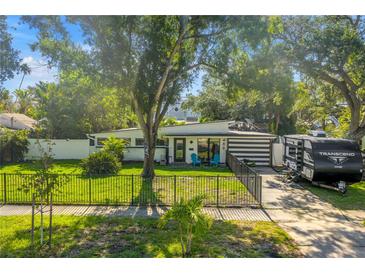 Charming single-story home with a well-maintained lawn, mature trees, and a black fence at 489 W Davis Blvd, Tampa, FL 33606