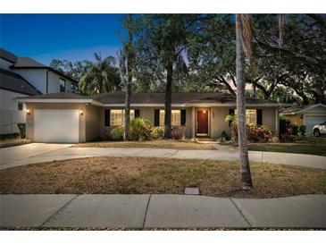 Charming single-story home with a well-manicured lawn, mature trees, and a welcoming front entrance at dusk at 3907 W Azeele St, Tampa, FL 33609