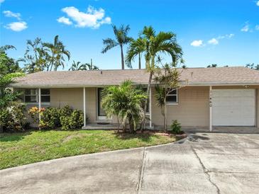 Charming single-story home featuring a lush tropical landscape, a one-car garage, and a well-maintained lawn at 11460 Park Blvd, Seminole, FL 33772