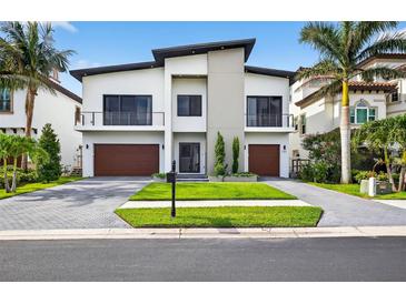 Modern two-story home boasting a manicured lawn, dual garages, and minimalist design against a clear sky at 131 Forest Hills Dr, Redington Shores, FL 33708