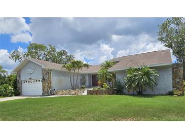 Charming single-story home featuring a well-manicured lawn, palm trees, and a two-car garage at 2210 Bayou Dr, Holiday, FL 34691
