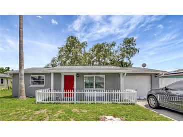 Charming single story home featuring a red door, picket fence, and well manicured lawn at 3426 Coldwell Dr, Holiday, FL 34691
