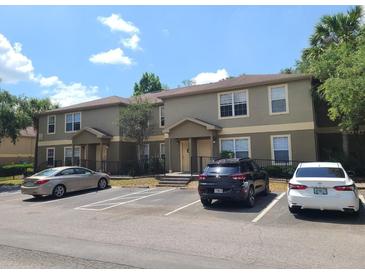 A tan two-story townhouse with parking in front and a well-maintained landscape, creating an inviting curb appeal at 36137 Lake Chase Blvd # 102, Zephyrhills, FL 33541