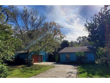 Charming single-story home with a vibrant blue exterior, mature trees, and a lush green lawn at 5017 E 127Th Ave, Temple Terrace, FL 33617