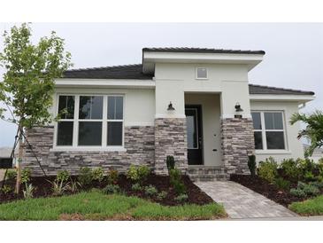 A modern home with a stone facade, and lush landscaping leading to the welcoming front door at 719 Allora Ave, Nokomis, FL 34275