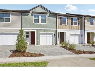 Townhome exterior featuring attached garages, brick driveway, and colorful siding details at 7683 Deer Valley Circle, Tampa, FL 33635