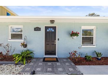 Charming front door with modern tile walkway, decorative plants and hanging flower baskets, providing great curb appeal at 1406 Nebraska Ave, Palm Harbor, FL 34683
