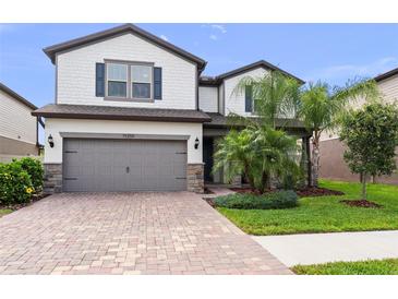 Charming two-story home showcasing a brick driveway, a two-car garage, and well-manicured landscaping at 19259 Mossy Pine Dr, Tampa, FL 33647
