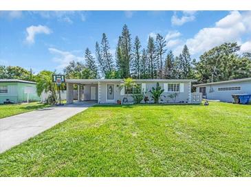 Charming single-story home with a well-manicured lawn, carport, and inviting curb appeal at 296 Huntington Dr, Largo, FL 33771