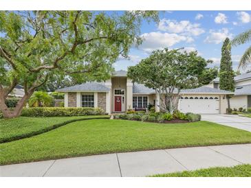 Charming single-story home featuring lush landscaping, brick accents, and a welcoming front entrance at 5604 Pine Bay Dr, Tampa, FL 33625