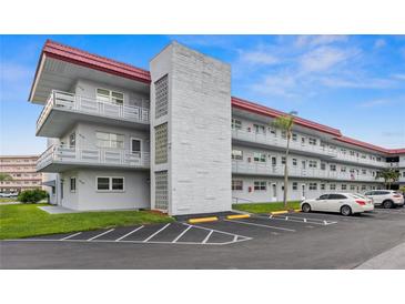 Exterior view of a three story condo building with a red roof and multiple balconies at 5660 80Th N St # B106, St Petersburg, FL 33709