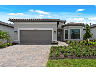 Beautiful single-story home featuring manicured landscaping, brick driveway, and neutral exterior color palette at 6072 Silver Grass Ct, Nokomis, FL 34275