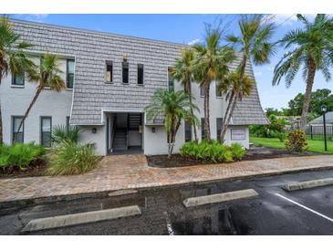 Charming condo building featuring lush landscaping and covered entryway to units on the second floor at 720 Lyndhurst St # 1101, Dunedin, FL 34698
