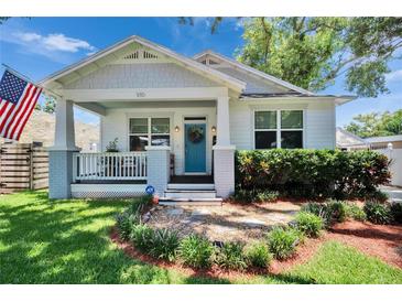 Charming single-Gathering home with a welcoming front porch, blue front door and well-manicured landscaping at 910 E Crenshaw St, Tampa, FL 33604