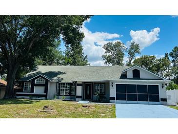 Charming single-story home with a well-manicured lawn, attached garage, and mature trees at 10444 Fordham St, Spring Hill, FL 34608