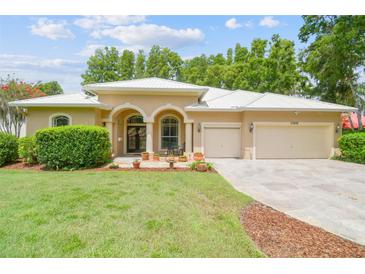 Beautiful tan single-story home with a manicured lawn, clean landscaping, and a white roof at 17906 Loretta Ln, Lutz, FL 33548