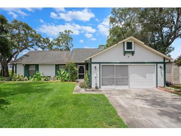 Charming single Gathering home with beautiful lawn, white siding, green trim, and attached two car garage at 5301 Bayonne Ave, Spring Hill, FL 34608