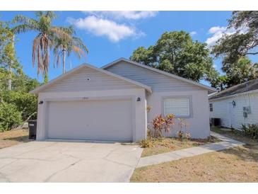 Charming single-story home featuring a two-car garage, landscaped yard, and traditional architectural details at 1004 Osage St, Clearwater, FL 33755