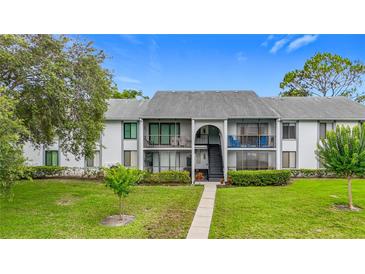 Inviting two-story condo with well-manicured lawn and access stairs to the upper units at 1207 Pine Ridge W Cir # H2, Tarpon Springs, FL 34688