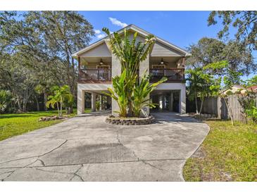 Inviting two-story home featuring dual balconies and a unique stilt foundation with landscaped yard at 5908 Mohr Rd, Tampa, FL 33615