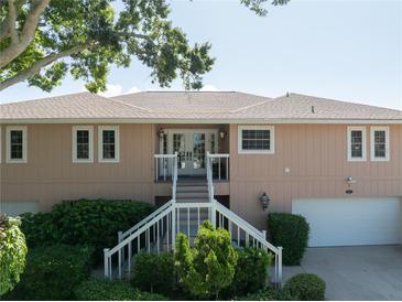 Charming two-story home with landscaped yard, featuring a staircase leading to the front door and an attached garage at 6663 Bayou Grande Ne Blvd, St Petersburg, FL 33702