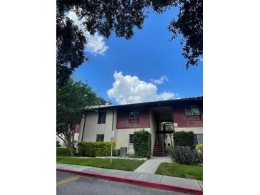 Apartment complex exterior with lawn and trees on a sunny day at 8636 Tahoe Ct # 13, Tampa, FL 33614