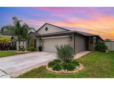 Charming single-Gathering home with well-manicured lawn, lush landscaping, and two-car garage at sunset at 9514 Channing Hill Dr, Sun City Center, FL 33573