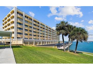 Low angle exterior of building with waterfront access and lush green lawn at 100 Bluff View Dr # 308A, Belleair Bluffs, FL 33770