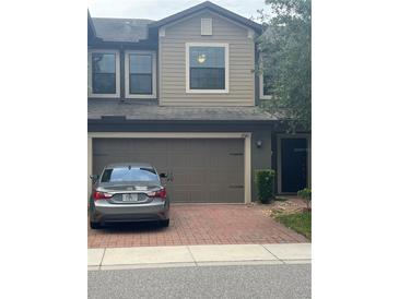 Two story townhome featuring an attached garage and brick paved driveway at 17361 Old Tobacco Rd, Lutz, FL 33558