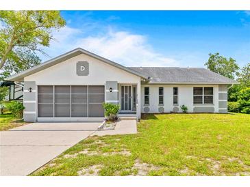 Charming single-story home with a well-maintained lawn, screened garage door, and classic design details at 12546 Brookside St, Spring Hill, FL 34609