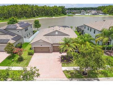 Beautiful home boasts lush landscaping and a brick driveway leading to a three-car garage and lake view at 1830 Cameron Ct, Trinity, FL 34655