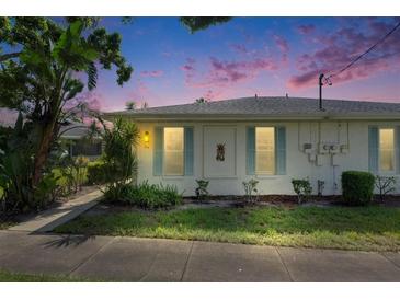 Charming white home with blue shutters, lush landscaping, and a welcoming dusk sky at 1903 Canterbury Ln # B24, Sun City Center, FL 33573