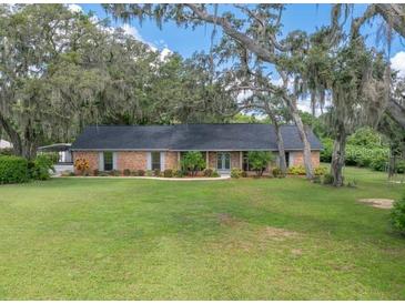 Sprawling single-story brick home with expansive front lawn and mature shade trees at 302 Old Mulrennan Rd, Valrico, FL 33594