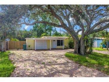 Charming yellow single-story home with a brick driveway and large shade tree in the front yard at 914 Sandpiper Way S, St Petersburg, FL 33707